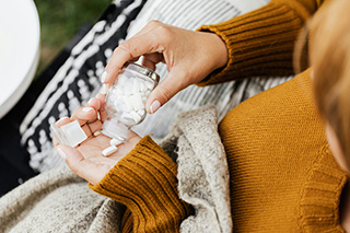 Una donna versa nella propria mano delle compresse da una boccetta